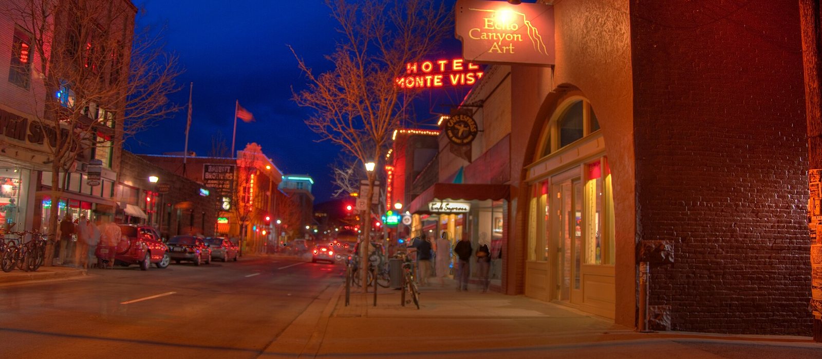 Downtown Flagstaff at dusk, with lit storefronts and the Hotel Monte Vista sign along the street